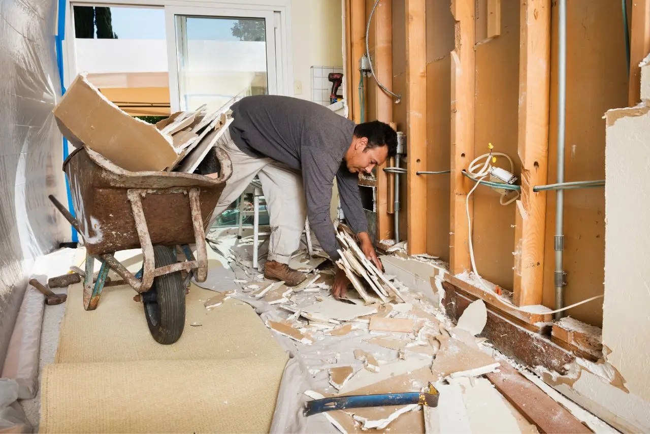 Man removes drywall debris into wheelbarrow during post-construction cleaning