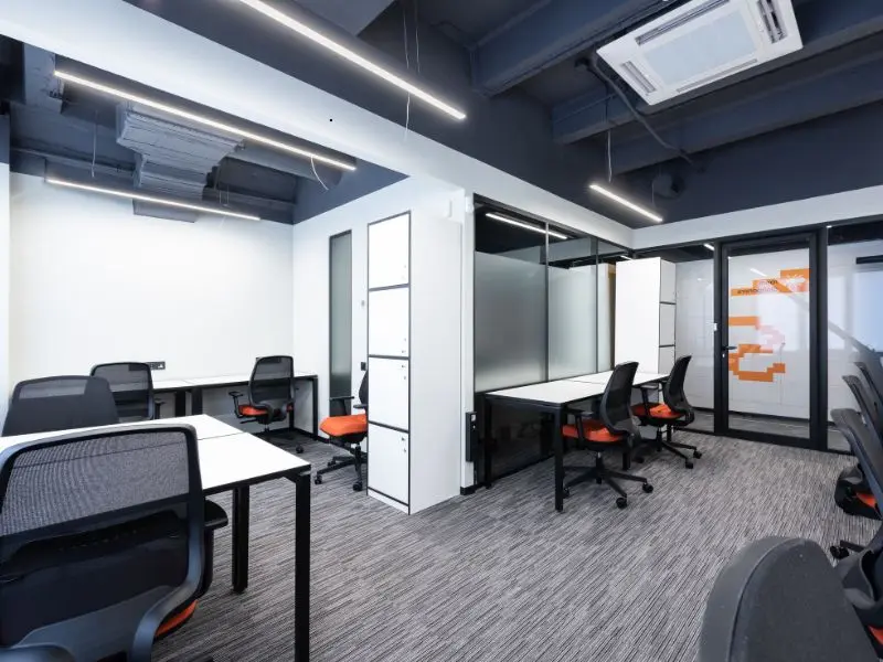 Clean modern office with gray carpet flooring and black ergonomic chairs in a tidy workspace.