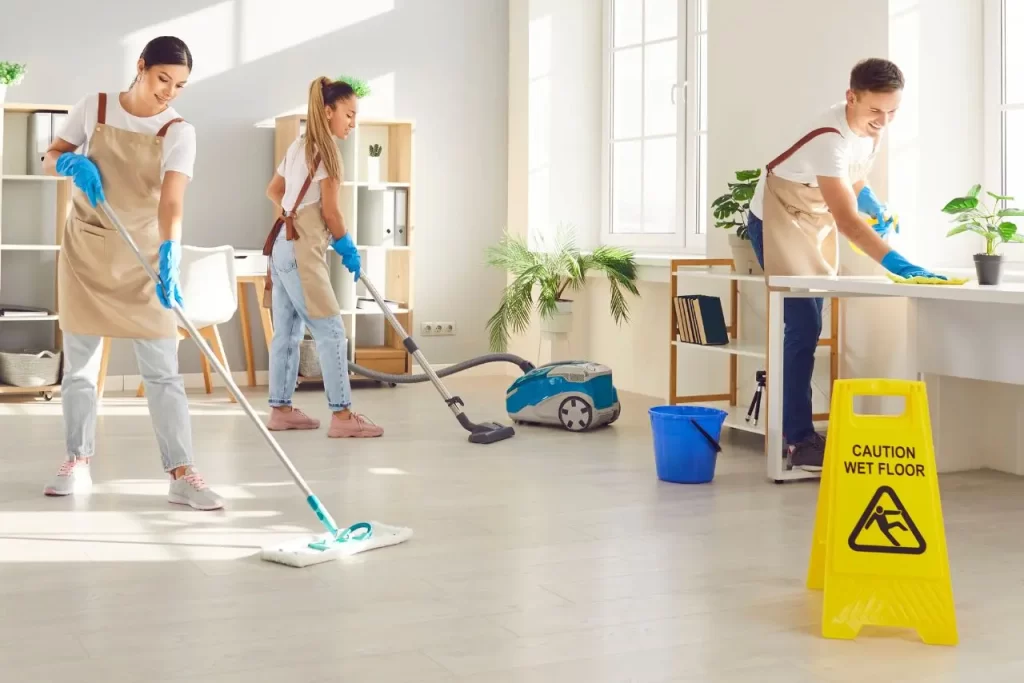 Cleaning team mopping, vacuuming, and wiping surfaces in a bright office using commercial cleaning janitorial services.