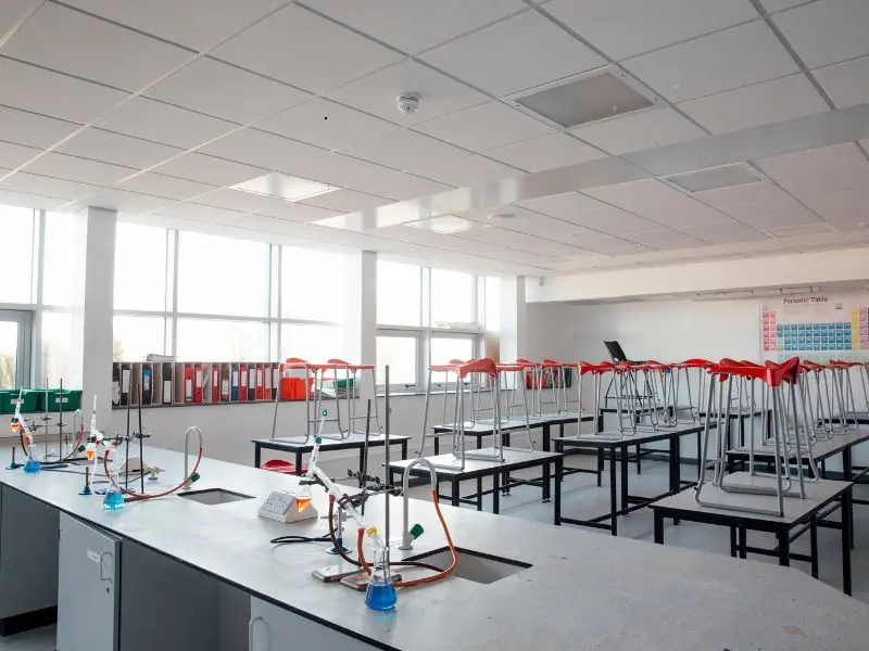 Empty school science lab with desks, stools, and sinks.
