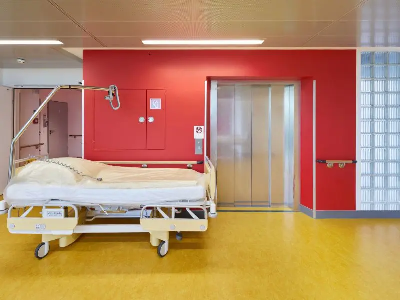 Patient bed near hospital elevator in a sanitized area maintained through hospital cleaning services.