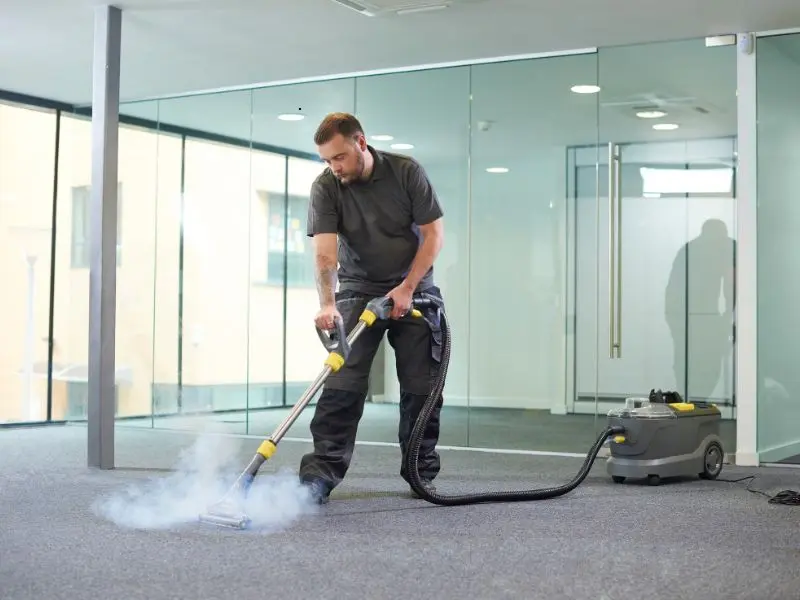 Man using steam cleaning machine on office carpet.