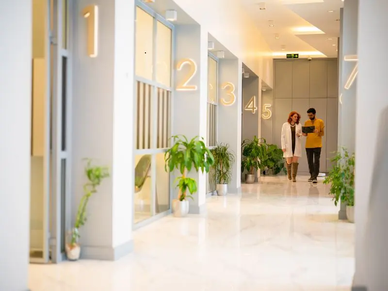 Modern medical offices with shiny white floors and numbered doors in a clean, well-lit hallway.