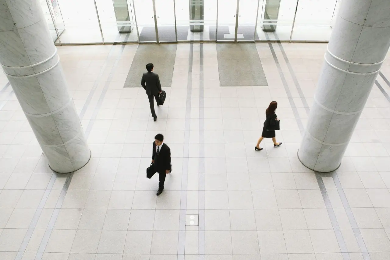 Business people walking across clean tiled lobby floor.