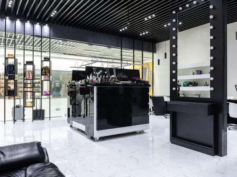 Modern beauty salon with glossy white floors and organized makeup stations in a clean, stylish interior.