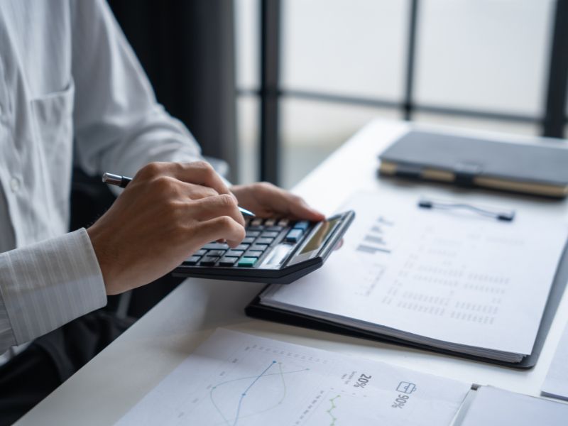 Man using calculator and reviewing financial documents to estimate cleaning service costs