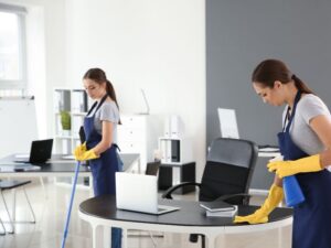 Professional cleaners disinfecting desks and organizing a modern office workspace between scheduled cleaning visits.