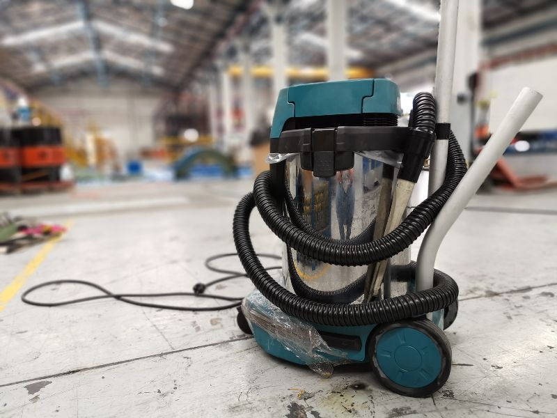 Industrial wet vacuum on a warehouse floor demonstrating the best way to remove cement dust after construction and concrete work.