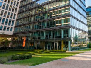 Modern office building with a glass facade, landscaped lawn, and paved walkway surrounding the corporate property.