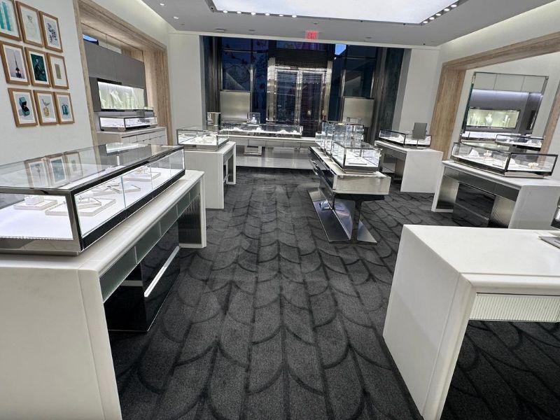 Encapsulation carpet cleaning in a luxury jewelry store with display cases and patterned gray carpeting.